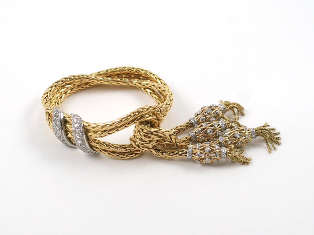 A French passementerie bracelet designed as a loop of two 18K Gold chains decorated with single-cut diamonds,  suspending four tassels on similar chains, each adorned with a cage like structure set with single-cut diamonds and finer gold chain,