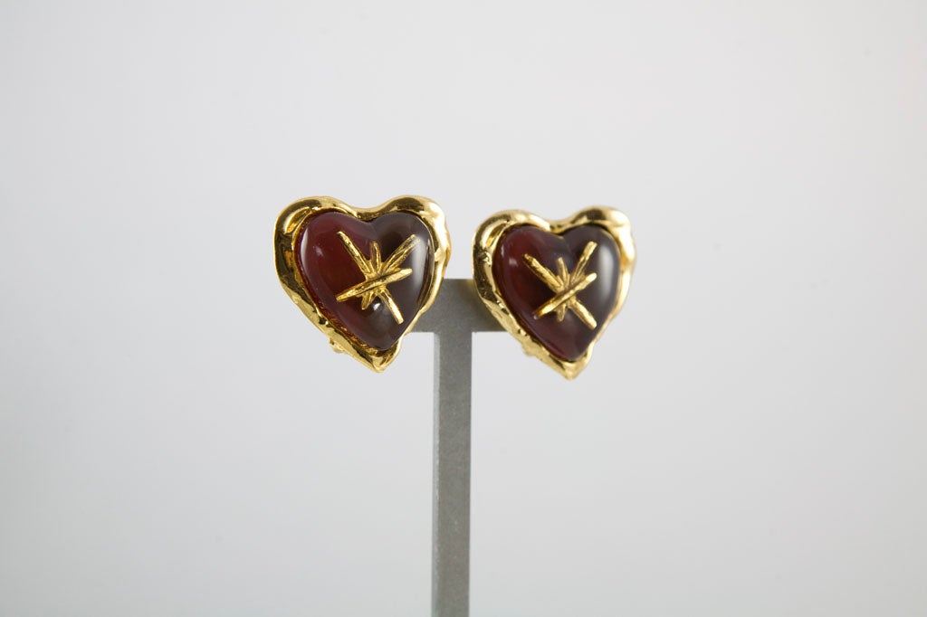 Great looking pair of clip on earrings from the house of Lacroix.  Featuring gold tone settings with resin hearts encasing starbursts and ruby red backing.