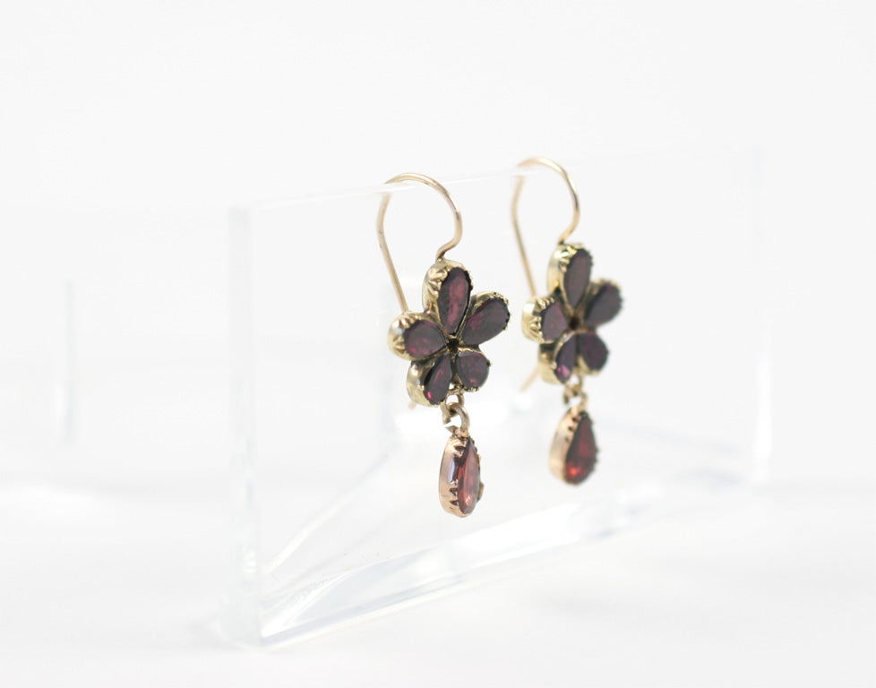 Wine and flowers combine to form garnet drop earrings from the late georgian era c.1840. The flowers are pansies, a posy of choice at this time for its romantic  sentiment. Pansy comes from the french ponsee, or 