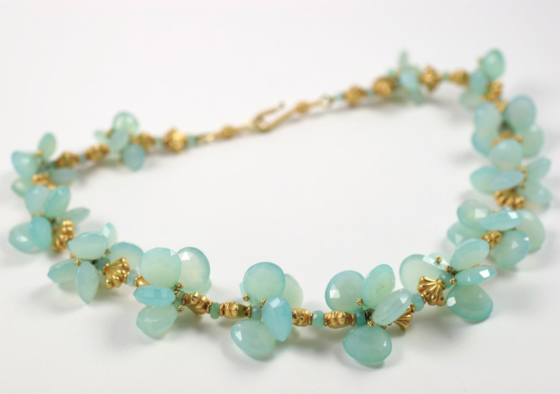 A Peruvian opal and 22kt yellow gold necklace. The Peruvian opal teardrop beads are wire wrapped in 22kt yellow gold and are formed into clusters. The clusters are separated by 22kt yellow gold shell beads and Peruvian opal faceted beads. The clasp