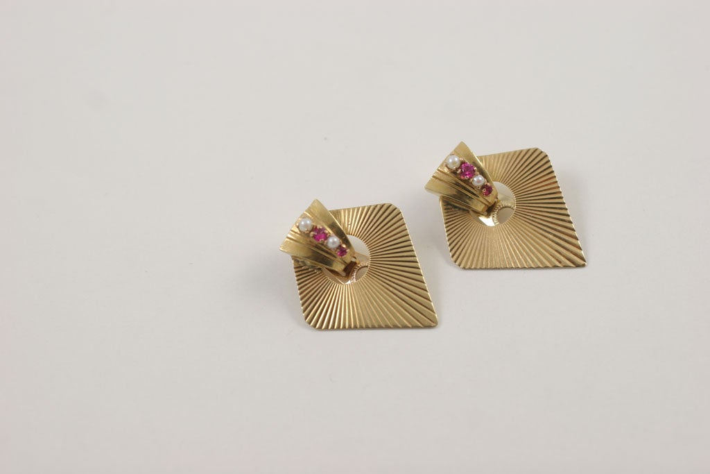 Geometrisch 14kt Y.G. Clip-Ohrringe.  Diamantförmige Platte mit strahlenförmigen Rippen. Boden mit ausgestelltem dreidimensionalen Abschnitt, besetzt mit 2 natürlichen Rubinen und 2 Zuchtperlen. Gewicht: 11dwt
