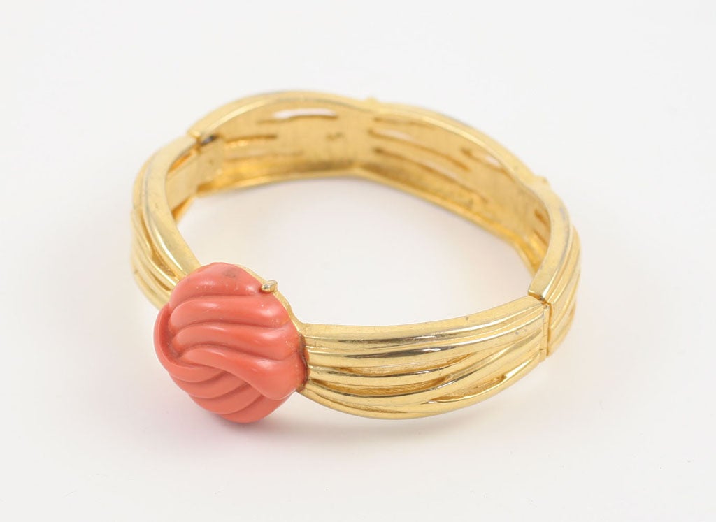Goldtone clamp bracelet with center knot of faux coral.