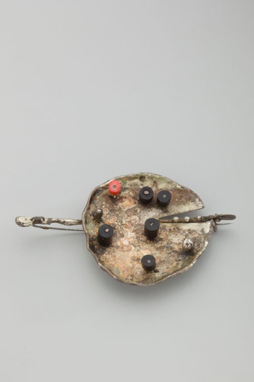 A sterling silver brooch by American master sculptor, Harry Bertoia (1915 - 1978).  In this piece Bertoia has applied a patina to his welded silver and decorated the surface with black and red plastic disks.  it is a strong example of Bertoia's