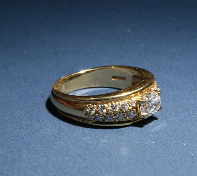An 18 karat yellow gold  band with 21 full cut diamonds by Boucheron.  The ring which features a .60 carat center stone is highlighted on either side by 20 smaller diamonds.  The diamonds are of high VS quality and G  color.  Overall, the ring has