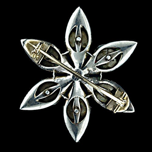 An exceptional Antique silver diamond brooch fully encrusted with old mine cut diamonds. A 1.20 carat old mine cut diamond centers this six petaled flower which undulates with sparkling antique diamonds. The brooch is crafted in silver with a 14