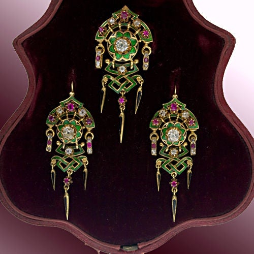 An exquisite antique pin/pendant and earring ensemble of a distinctly French flavor with an oriental influence. Vivid green guilloche enamel contrasts with old mine cut diamonds and rubies set in butter cup rosettes. For added interest the dagger