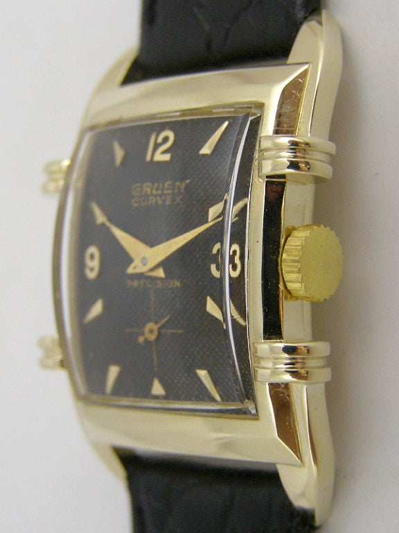 Gruen Curvex 14K YG very elaborate and striking case design circa 1950's with wide bezel and 2 prominent split ribs on either side of the case. Featuring black original dial with gold raised indexes and tapered dauphine hands. Dial signed Gruen