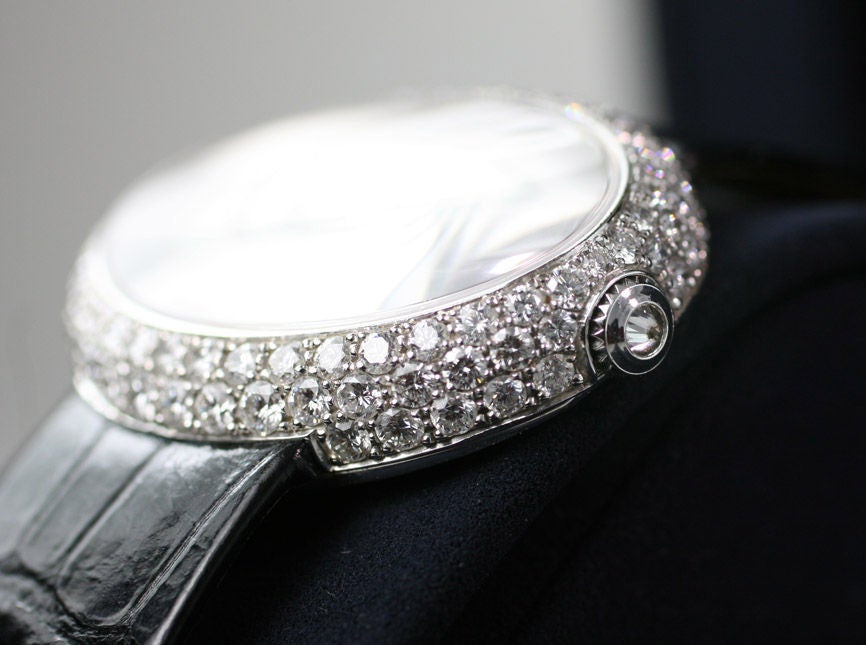 This is a elegant Piaget 18k white gold, diamond & white mother of pearl lady's watch. The movement is quartz and it comes on a black satin strap with a Piaget 18k white gold and diamond buckle.