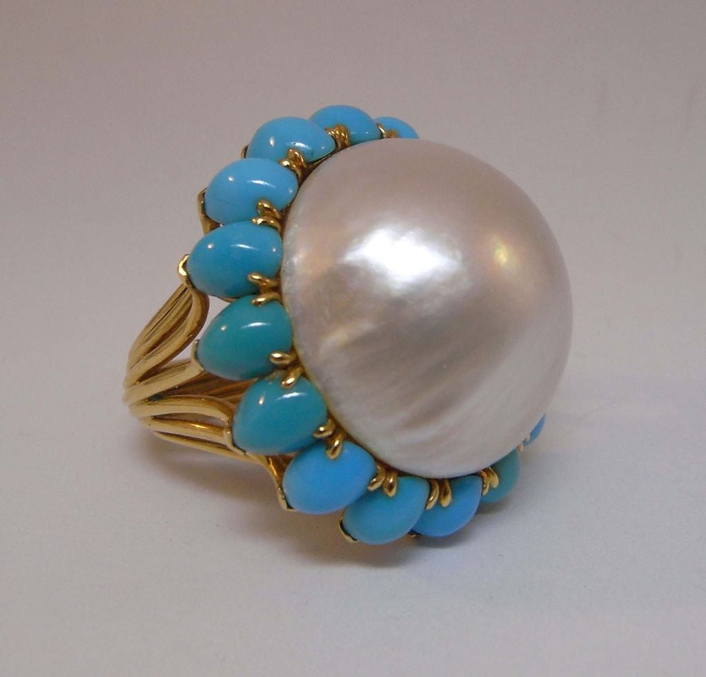 A fantastic cocktail ring by Cartier Paris, with an 18kt gold wire shank leading to an enormous mabe pearl surrounded by turquoise 'petals'.  Signed 'Monture Cartier' and marked with the eagle's head poincon for 18kt gold.  Ring size US 6.5, and