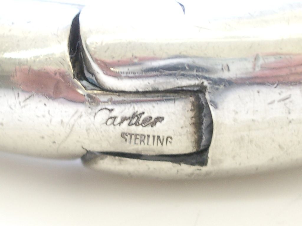 A sculptural bracelet by Cartier. The hinged sterling silver oval bangle bracelet measuring 1 1/2