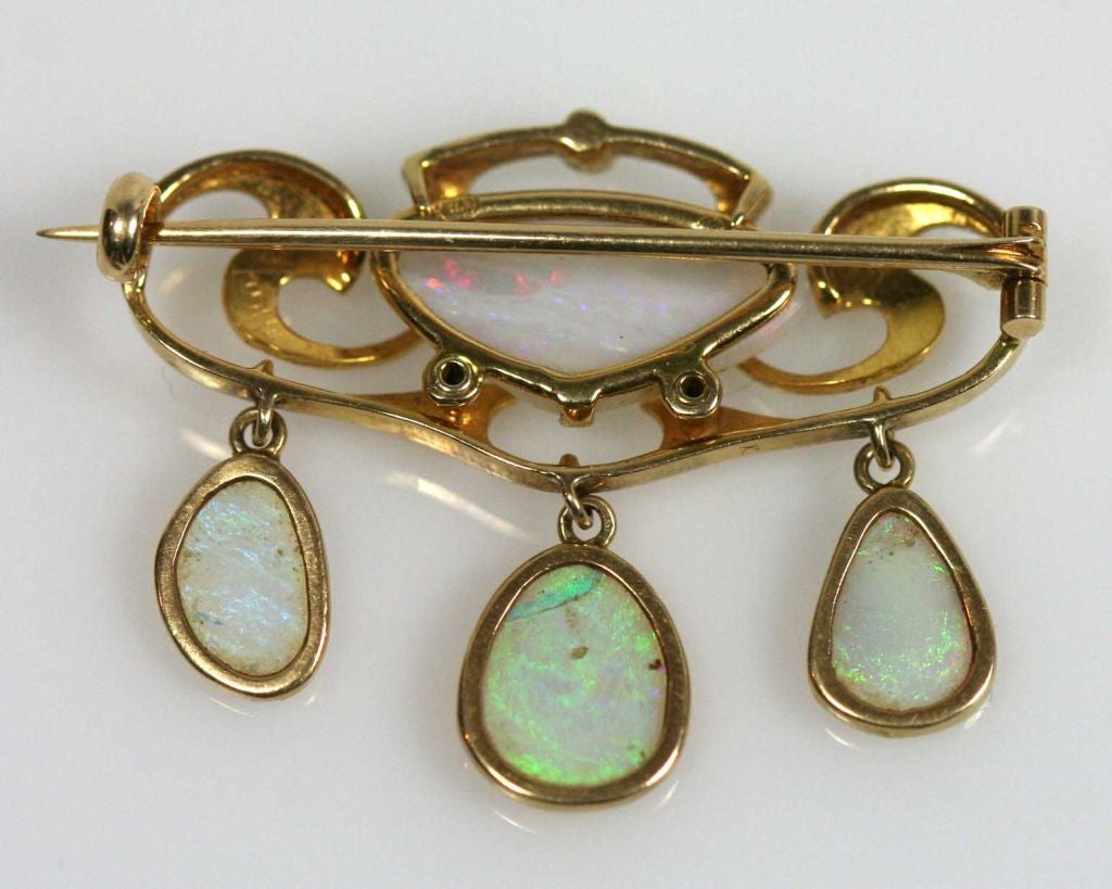 English Arts & Crafts period 15 carat gold and opal brooch by Liberty of London.  Designed by Archibald Knox for the Murrle Bennett & Co circa 1910-15. This brooch features a curvelinear setting for a central white opal and three opal drops.  This