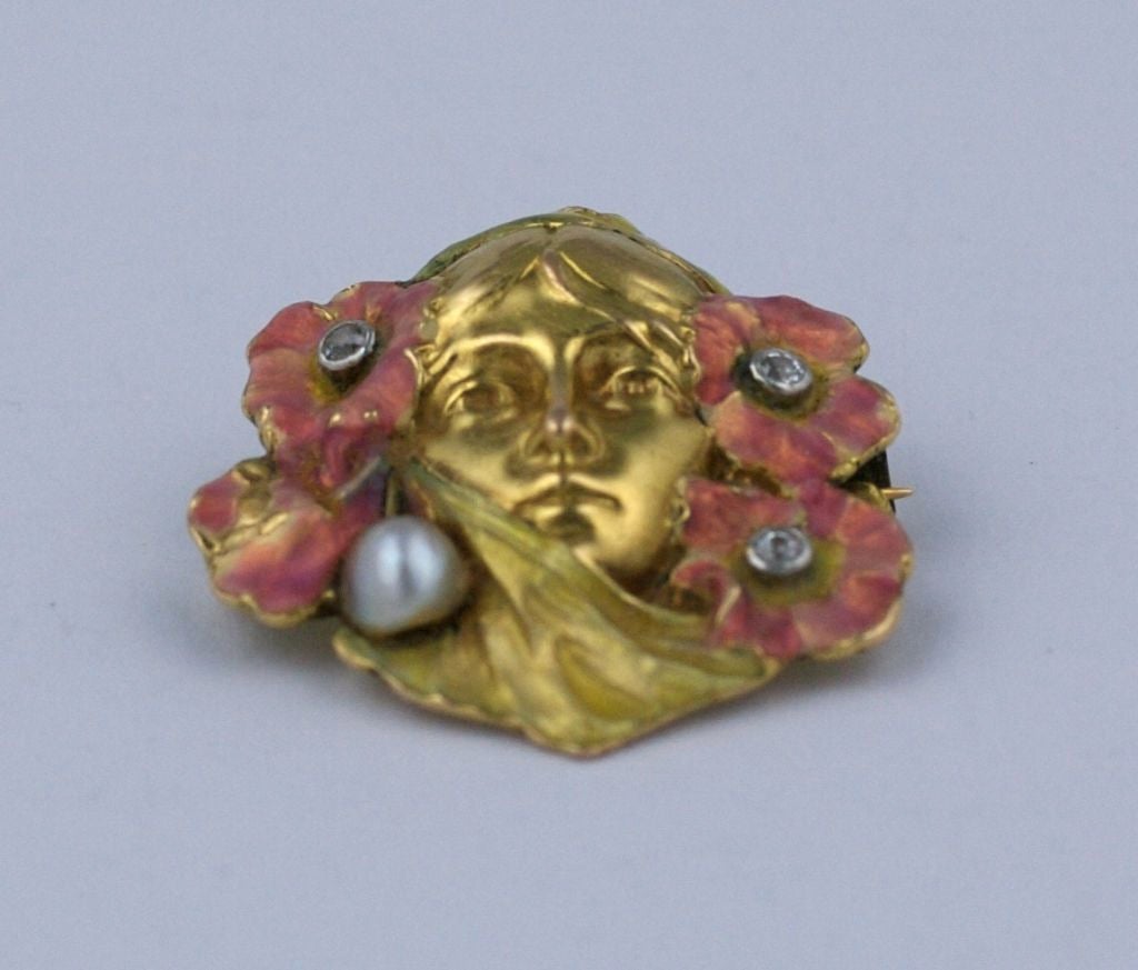 Lovely Art Nouveau brooch of a womans head shrouded in pink enameled poppies, set in 14k gold. Each flower has a diamond center and a pearl sits to the side. A beautiful period piece. 1890's USA.
Excellent condition. 