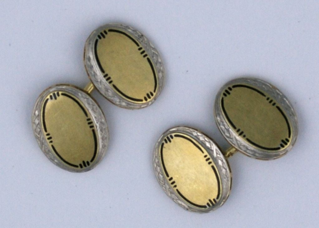 Élégants boutons de manchette en or 2 tons avec émail noir. Galerie gravée en or blanc avec centre ovale en or jaune et émail. Excellent état, datant des années 1930.