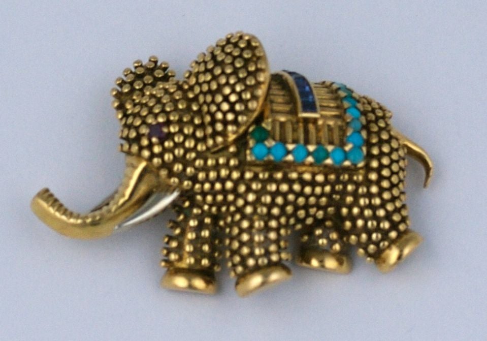 Playful LaCloche Elephant Clip Brooch from the 1950's in 18k gold with gem stones. Charming rendition of a pebble finished elephant with calibre cut sapphires across his blanket edged with Persian turquoise cabochons. Tusks rendered in white gold.