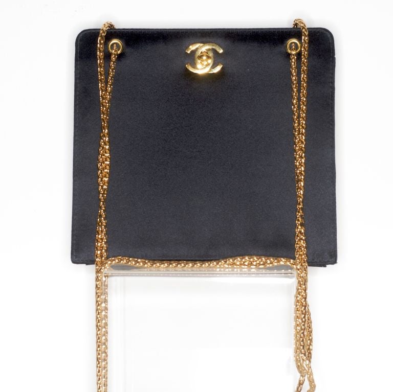 Beautiful and unworn black silk Chanel bag with long gold chain straps and gold leather interior.