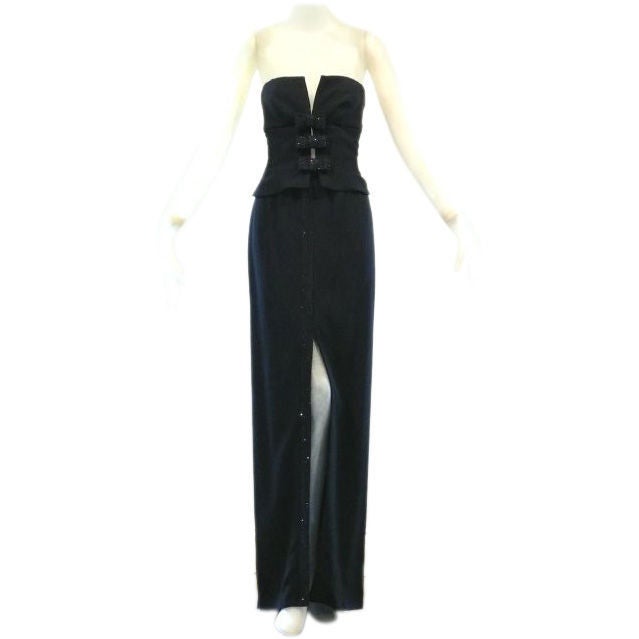 A beautiful and elegant narrow column gown inspired by a man's tuxedo with glittering black on black sequin bows and sequin detail running the front of the gown along a high slit. The dress appears to be two pieces but is actually one.  Very