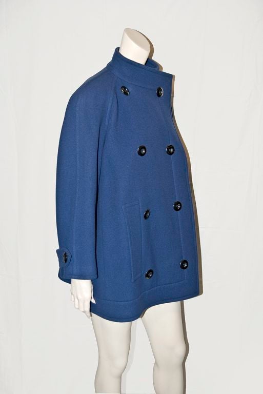 This Nina Ricci piece is a lovely shade of blue.. It can be best described as an over size pea jacket. It has a high stand up collar and front is double breasted with side slit pockets.<br />
The jacket has a wide body but wonderfully shaped. The