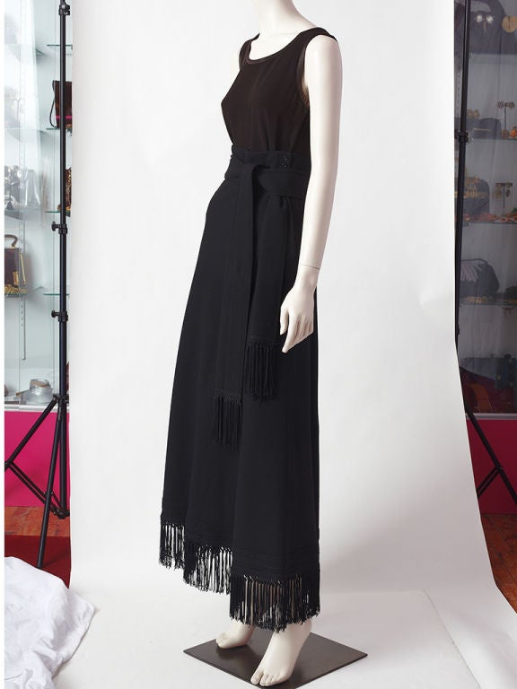 Anne Klein wool maxi skirt with fringe detail . Hem has a deep fringe and a long self tie belt ending in a fringe as well. Skirt body is slim fitting in the hips and flares out at the bottom. Wool is heavy weight giving a sculpted shape to the skirt.
