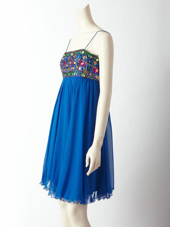 Malcolm Starr electric blue empire waist spaghetti strap cocktail dress. Dress bodice is embellished with large faceted colored stones and abstract shaped sequins in tones of emerald green, magenta and royal blue. The body of the dress is bias cut