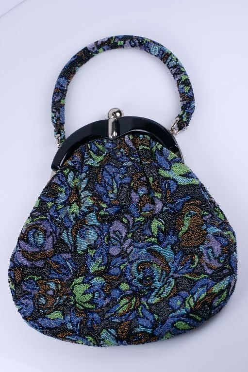 Unusual large beaded "pouch" style bag circa 1960 with black bakelite and chrome deco style frame. The heavily beaded florals are in copper,violet, blue,green and charcoal with large tubular beaded handle. Lined in peach rayon.<br