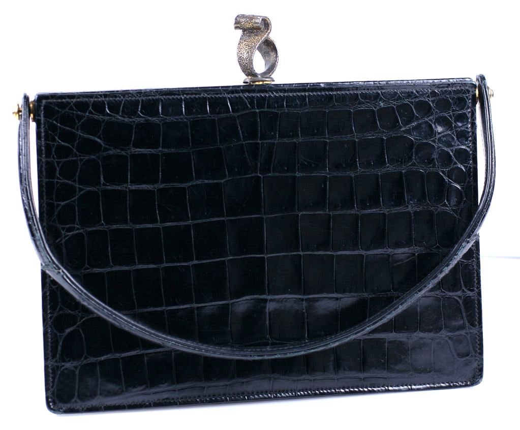 Chic envelope bag of French origin in center cut baby alligator retailed by Saks 5th Ave. Very slim elegant profile with gilt sterling swirl clasp bordered in pastes. Can be used as clutch with swing handle down.<br />
Measures 8