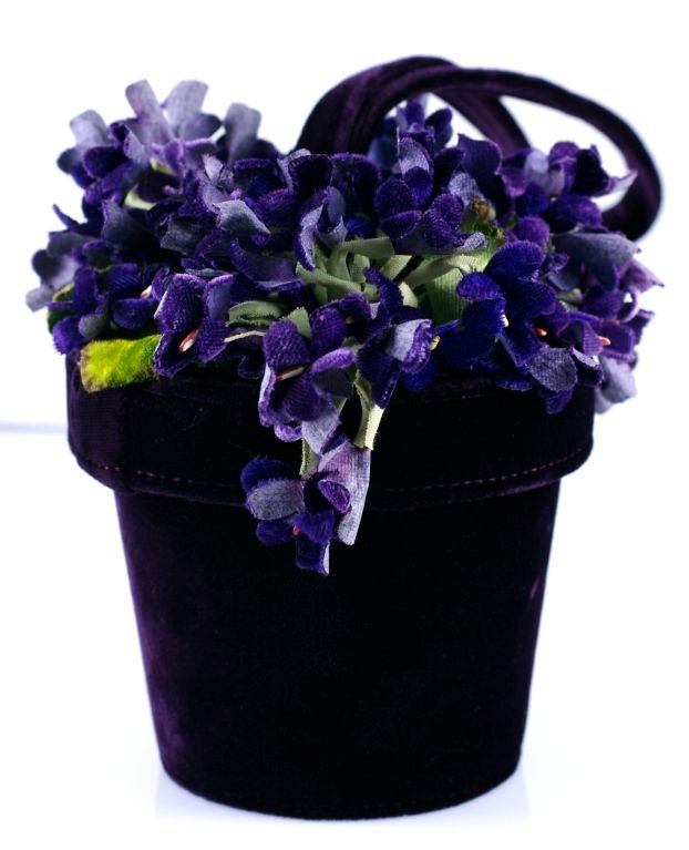 Lulu Guiness does Schiaparelli in this surrealist flower pot bag. The lid is decorated with silk violets which opens to enter bag.<br />
Deep purple velvet with self fabric handle.<br />
Height with handle: 14