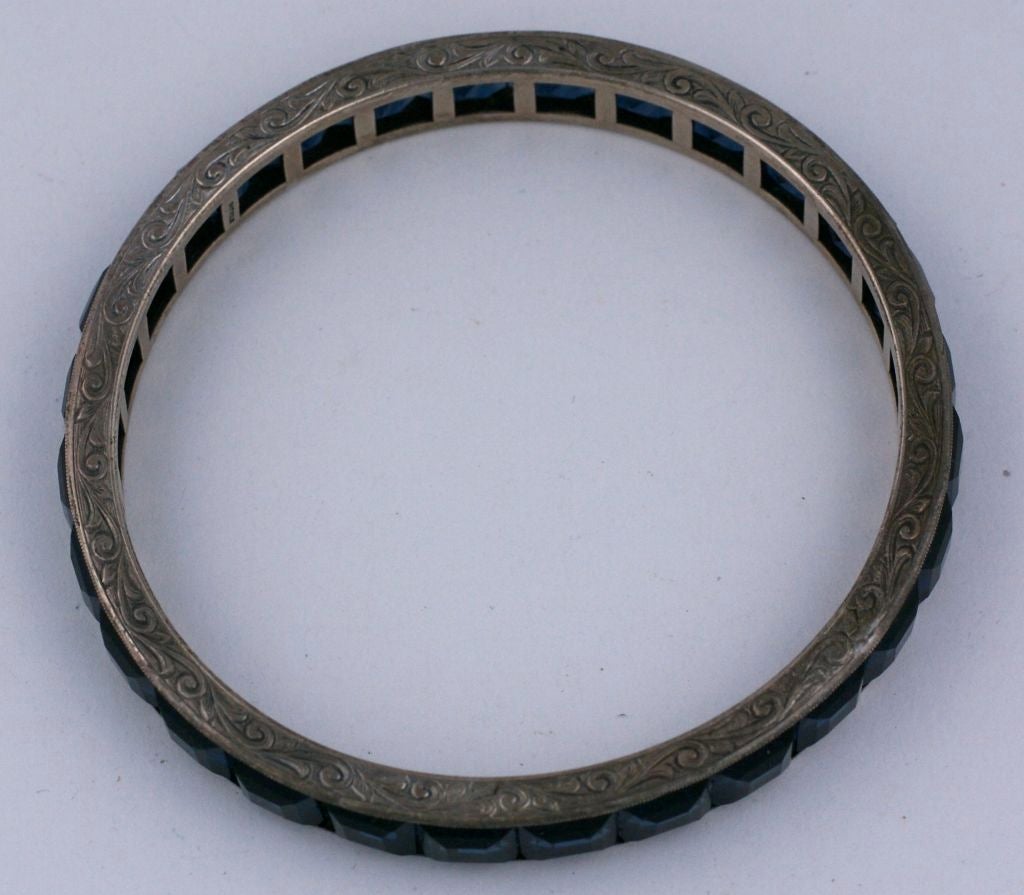 Les faux saphirs enchâssés confèrent à ce bracelet une allure élégante, idéale pour être empilée. Cette pièce d'époque déco est sertie en argent sterling et présente des gravures à la main complexes autour des épaules.<br />
Excellent état.<br