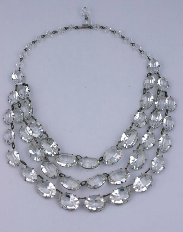 Collier plastron de taille inhabituelle composé de 3 brins de pâtes de verre ovales et étincelantes, serties de griffes, attachées à une chaîne réglable en perles de cristal. États-Unis d'Amérique, années 1930. Excellent état. 
Longueur de 16