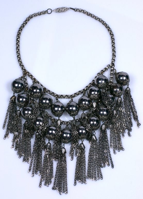 Large bib of high polish steel tone beads mixed with antique silver findings (textured caps,tassels and chains). Great to wear with black. Substantial scale and presence. Marcasite embellished torpedo clasp which screws apart for access.<br