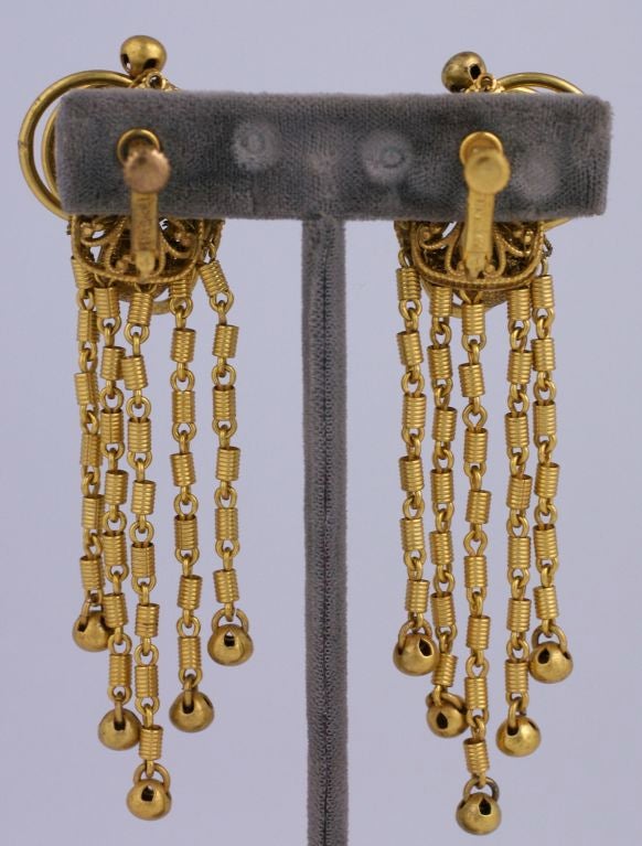 Miriam Haskell long fringe dangle earrings in signature russian gold plated metal. Floral filigrees are mixed with textured balls and rings. The fringe dangles are composed of small ribbed tubes ending in small gilded balls. <br />
Adjustable clip