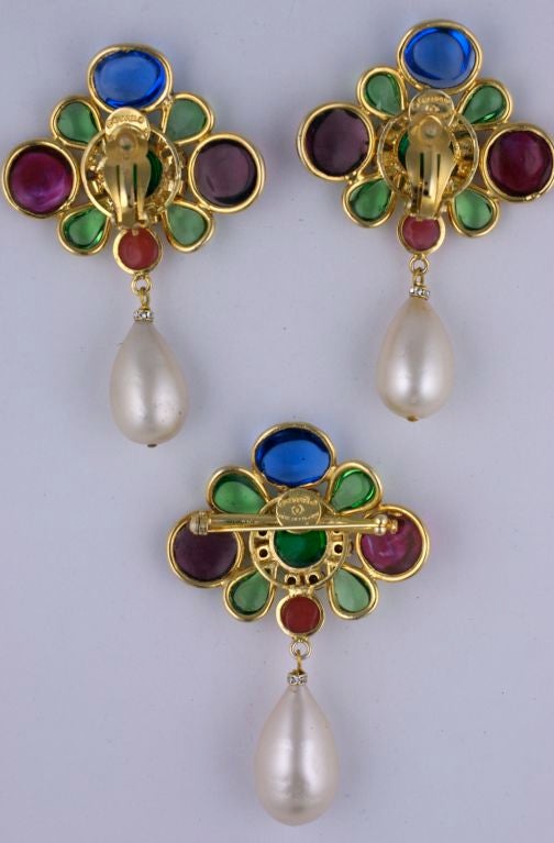 Signature Chanel Brooch and earring set made in Paris by Maison Gripoix in the 1980s. Large scale earrings and brooch are all the same size. Hand formed metal bezels with poured glass in shades in amythest,ruby, emerald and sapphire with Swarovski