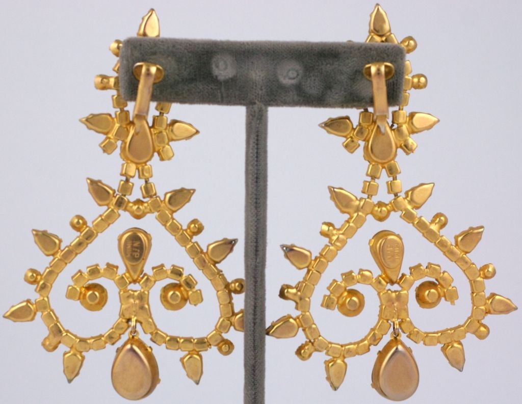 Boucles d'oreilles chandelier en strass à grande échelle par Mimi di Nardo. Des strass en péridot, aqaumarine et cristal forment un motif en forme de volute avec un grand cristal en forme de poire qui pend en dessous.<br />
Clip back.<br />
3.5