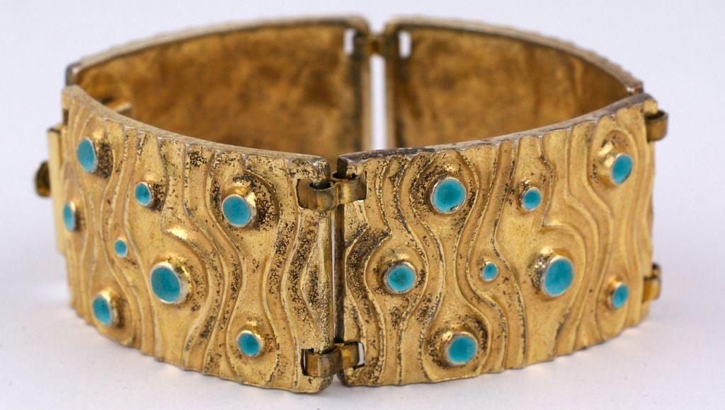 Attractive Modernist 1950s bracelet in gilt sterling with matte turquoise enamel. Undulating liquid swirls surround the recessed enamel wells. A very imposing bracelet with a great look. Excellent condition.
Signed 