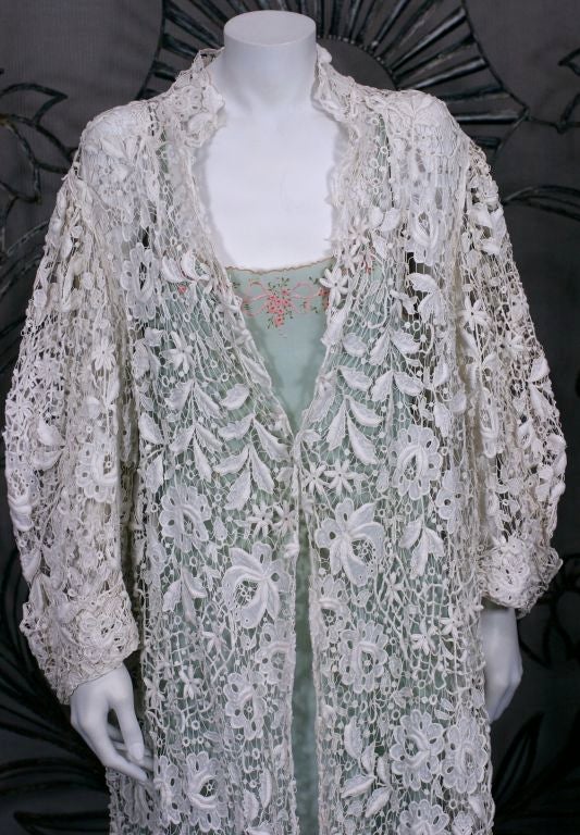 An unusual Edwardian three quarter length coat, hand embroidered to imitate lace. Embroidered with floral blooms, leaves and branches, incorporating techniques to imitate needle lace. The coat is cut full, with wide cuffed sleeves. 1890's
