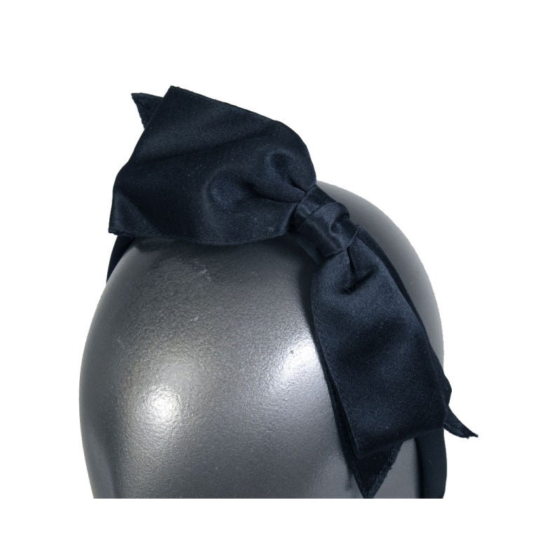 A gorgeous black satin bow adorns this satin covered headband from Chanel, Paris circa 1980. Never worn, the flexible band has the Chanel label stitched to the inside, and it still bears the original tag from Bergdorf Goodman in New York.  It comes