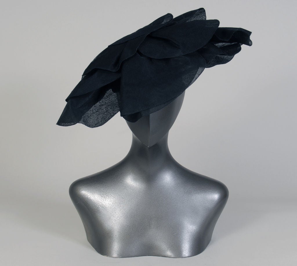 Created by Cristobal Balenciaga for a New York lady who was a member of the International Best Dressed List this hat is simply stunning.<br />
Perched at a jaunty angle the hat is composed of overlapping sheer black petals with a padded flower head