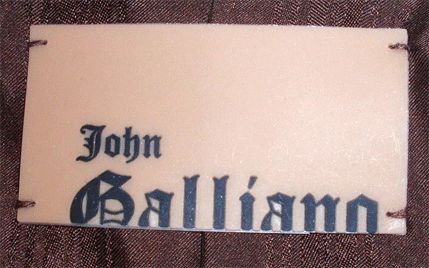This is a gorgeous white and brown rabbit fur coat by John Galliano, from 2000. It has two front open pockets, three wood buttons, and a brown silk logo lining. The coat measures 18