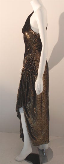 This is a black and gold one shoulder gown by Vicky Tiel, from the 1980's. The gown has gathering on the side hip, an uneven hemline, and a black silk lining.
