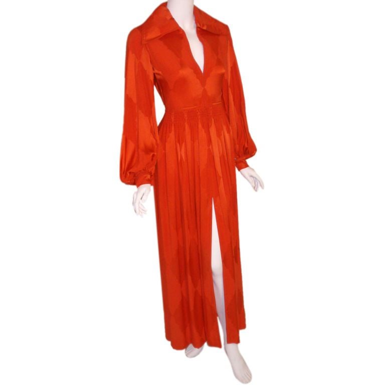 This is a long orange silk gown by Galanos for Amelia Gray, from the 1970's. It has a collar, long bell sleeves, fitted waist, slit in the front, and zips in the front.

This long orange silk gown by Galanos is available to be viewed privately in