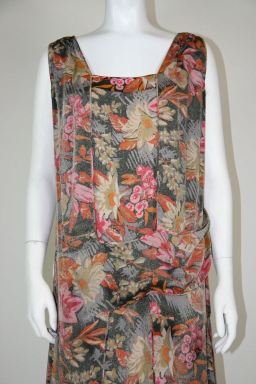 Stunning French silk lame´ 1920s party dress, with a Deco floral print in shades of red, pink and grey. Drop waist, wrap around front panel fastened with snaps. Sleeveless, square front neck with v-back. Kick pleats above the knees on the sides,