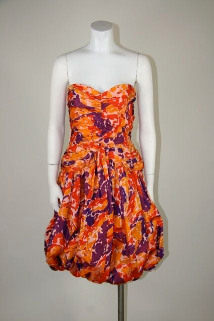 Bill Blass strapless cocktail dress. Orange and purple abstract chiné taffeta. The bodice is ruched and fitted with a sweetheart neckline. The ruched detail continues to the hip, but comes up at the waist in a peak. The skirt falls into a balloon.
