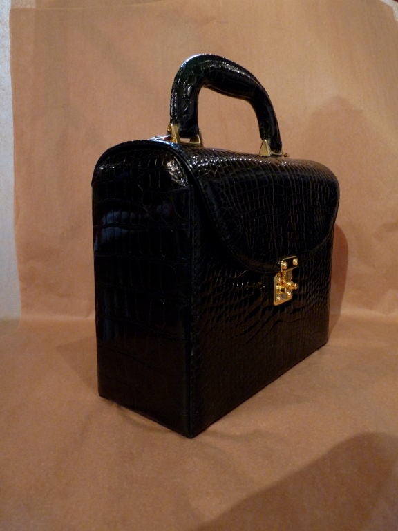 Glossy black baby crocodile handbag by Lana of London.  Handbag has gold-plated hardware with a pinch to open closure.  Also included is a leather-backed crocodile shoulder strap with gold-plated spring release clasp.  Purse comes with original