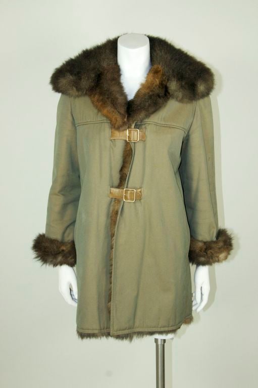 Olive cotton parka lined with nutria. European size 44. Two buckles in the front as closure, tan leather. Nutria fur collar. <br />
<br />
Measurements:-<br />
<br />
Bust - 44
