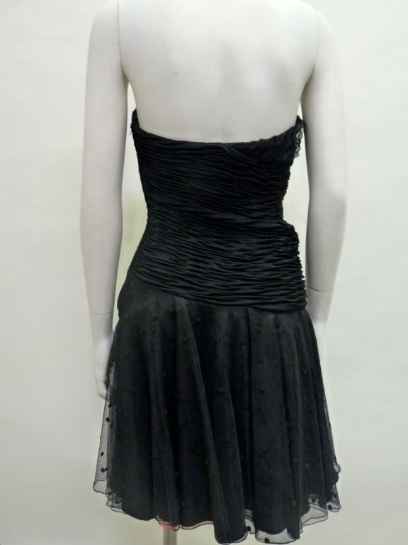 Loris Azzaro black cocktail dress. Strapless sweetheart neckline. Ruched silk jersey over left breast and down bodice to the hips. Flocked-net flounced skirt with red netted underskirt. 