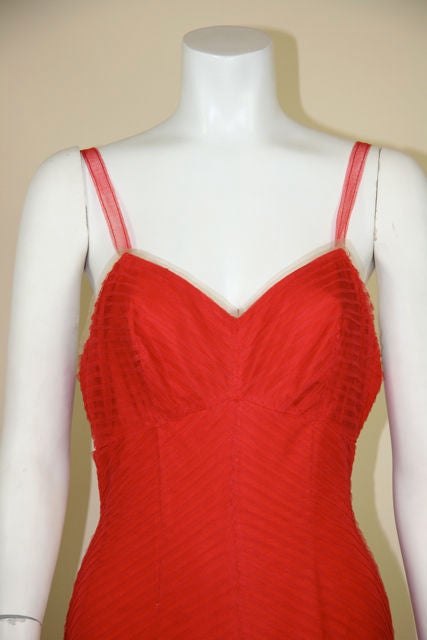 50s red tulle fishtail gown. Tulle spaghetti straps. Pintucked tulle with fitted bodice down to the knees. Red silk flowers at the right knee at start of fishtail flounce. Flounce is lifted with layers of tulle.<br />
<br />
Measurements:- <br