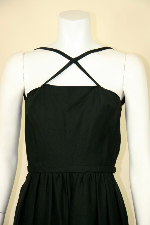 Silk black dress. Open V to mid back. Criss-cross detail across front with square neckline. Fitted at the waist with pleated skirt. Attached fabric belt. 
