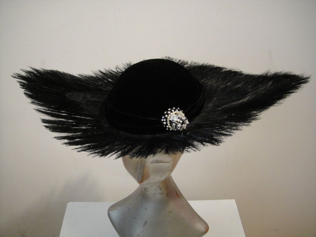 A high style 50s hat with graceful severity, black egret feathers trimmed into wide points on either side, with a rhinestone trimmed structured velvet cap. Lined in an unusual silk plaid with an adjustable drawstring.<br />
<br />
Inner