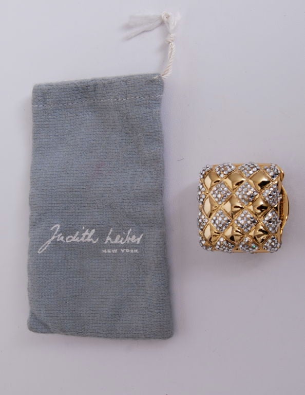 Gold tone metal with swarovski crystal inlay pill box with drawstring bag. Labeled Judith Leiber.