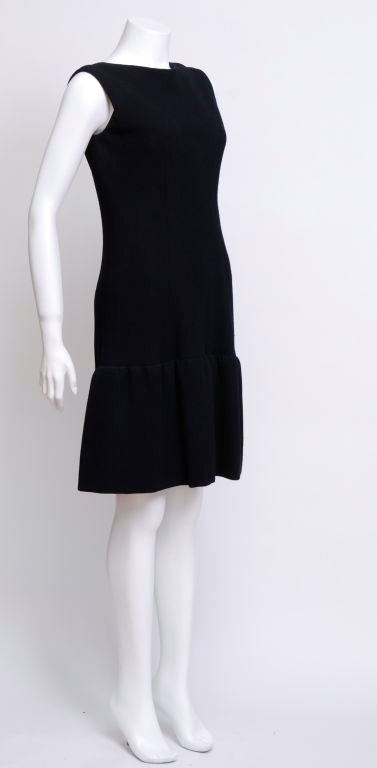 Heavy black silk crepe sleeveless dress, scooped back neckline and seven buttons running down the backside. It has a drop waist and a ruffled skirt. Fully lined in silk charmeuse.<br />
<br />
Norman Norell(born Norman David Levinson April 20,