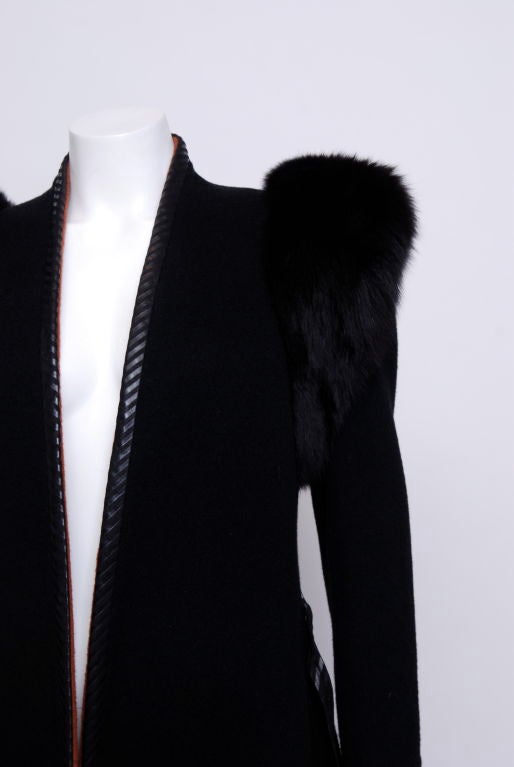 Black cashmere and wool mix coat with striped leather trim and exaggerated fox shoulders. Unattached is a striped leather belt. The coat is lined in brick colored casmere/wool mix.<br />
From the estate of Leona Helmsley.